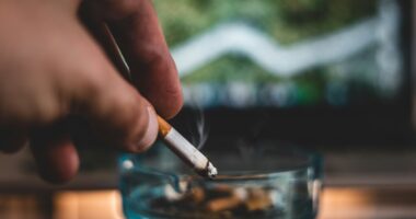 Close-up of hand putting out cigarette in ashtray