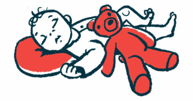 A red teddy bear rests on the side of a sleeping infant whose head is on a pillow.