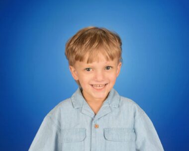 A standard school photo of a young boy in pre-K. The background is blue and the boy is smiling.