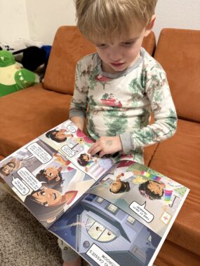 A boy sits on a couch leafing through the pages of a picture book