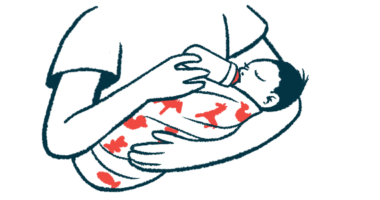 A baby in a person's arms drinks from a bottle.