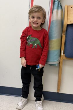 A 5-year-old boy smiles for a photo while having his height measured at the doctor's office.