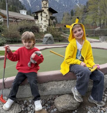 Two boys sit on a wall at a mini-golf course