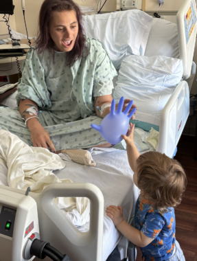 A woman is greeted at her hospital bed by a child with a balloon.